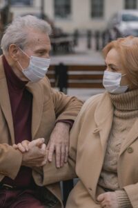 Old man and woman with masks on a bench